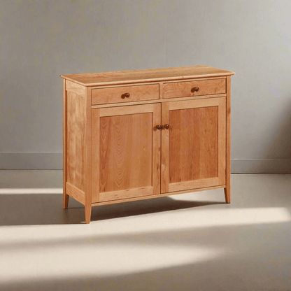 A Shaker style linen press with a solid wood frame and finish, featuring two doors and a drawer with metal knobs.